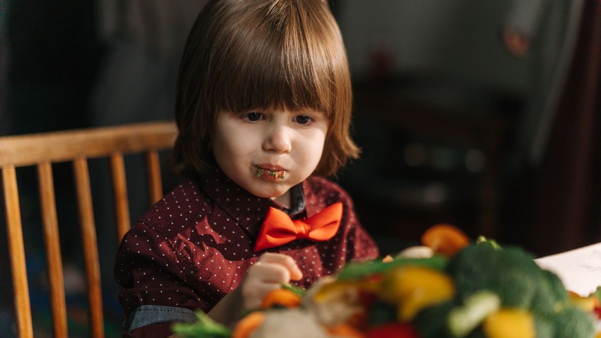 Adorable child enjoying fresh vegetables at the dinner table.